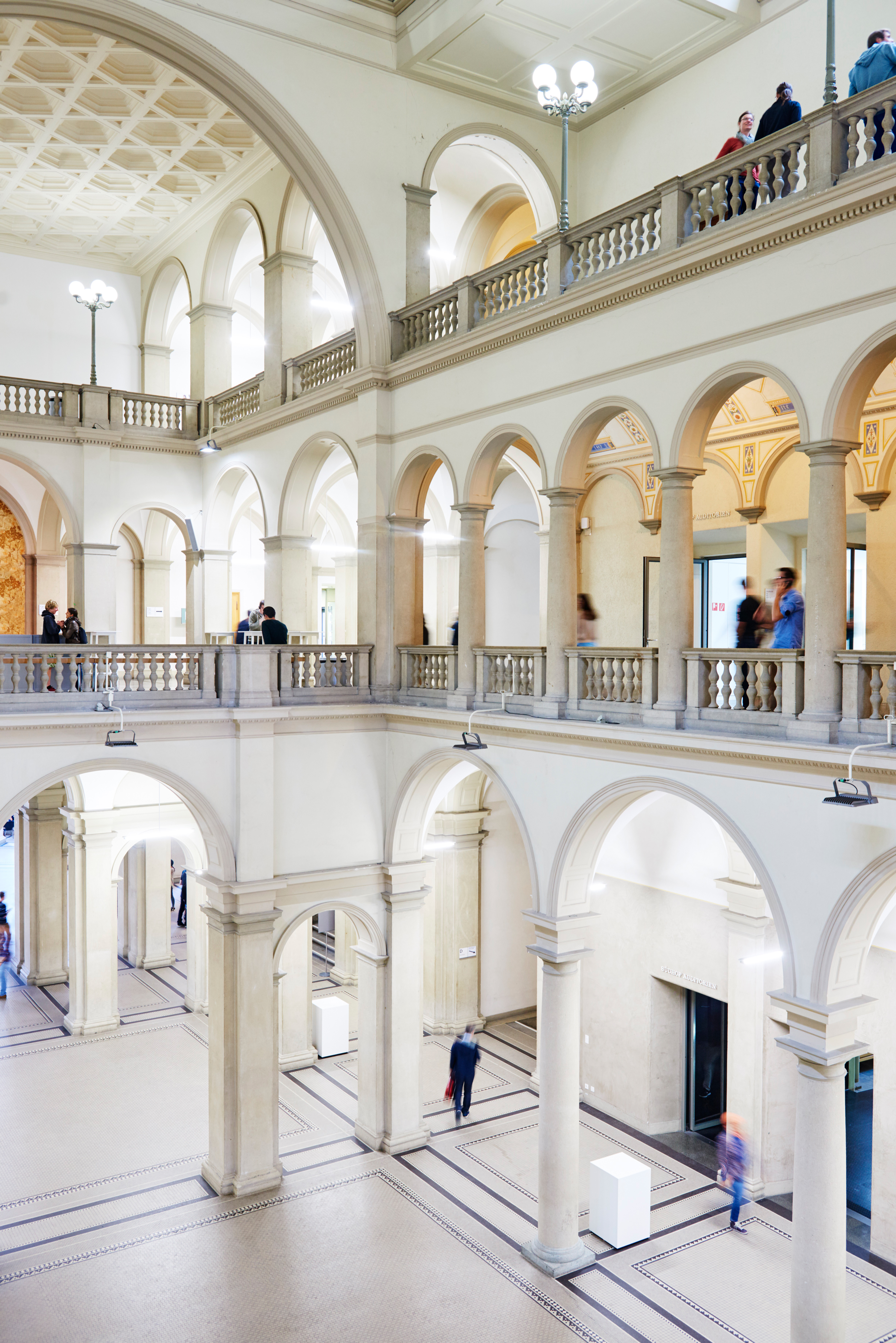 Historic ETH interior atrium with three-story classical arches, ornate balustrades, and natural light flooding the white marble space